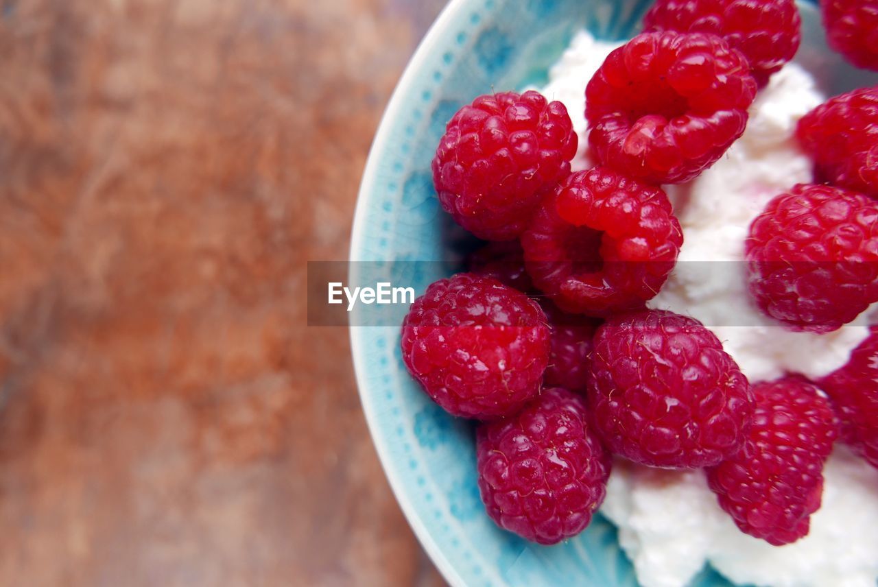 Directly above shot of raspberries with cottage cheese in bowl on table