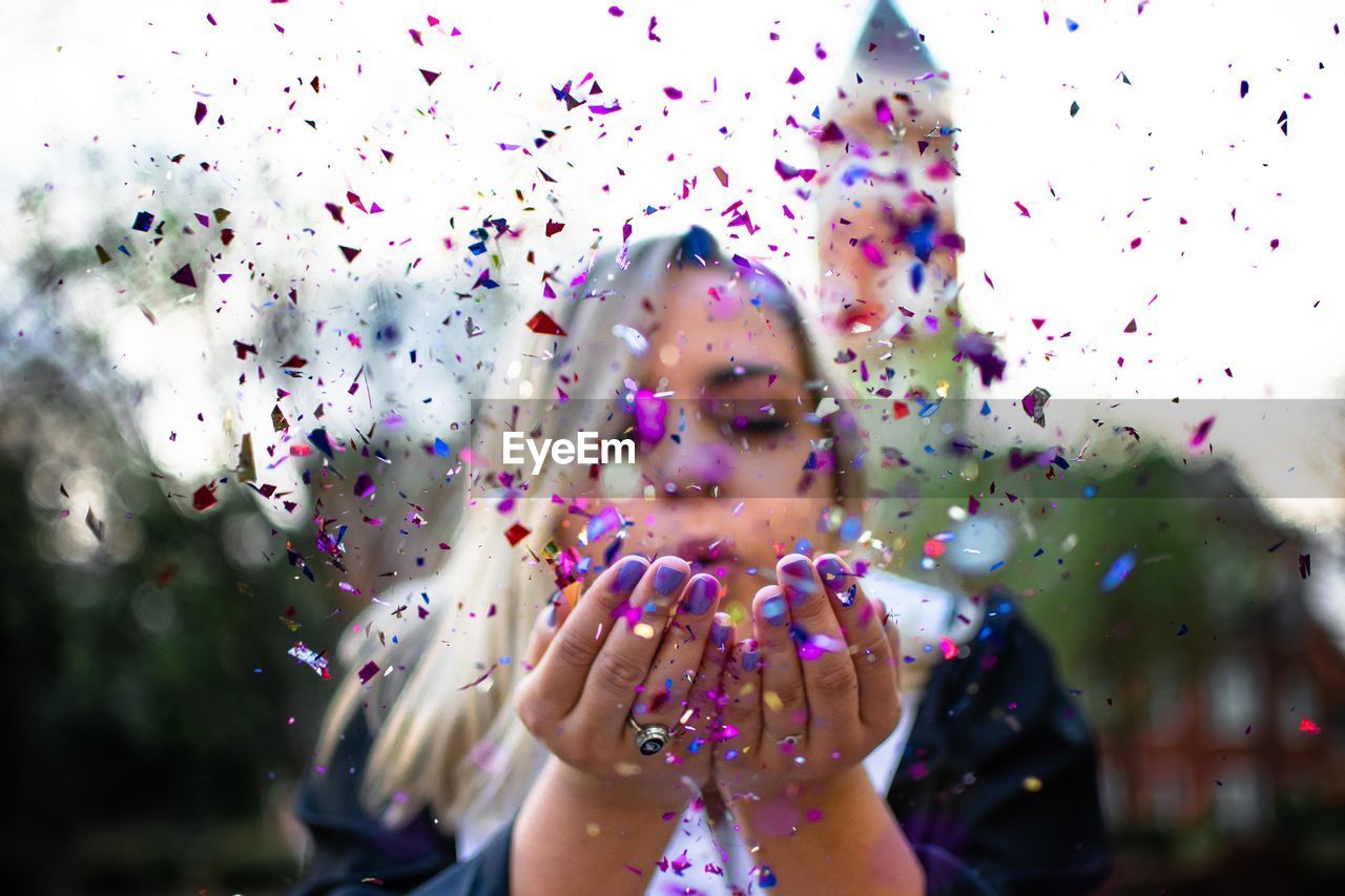 Woman blowing confetti outdoors