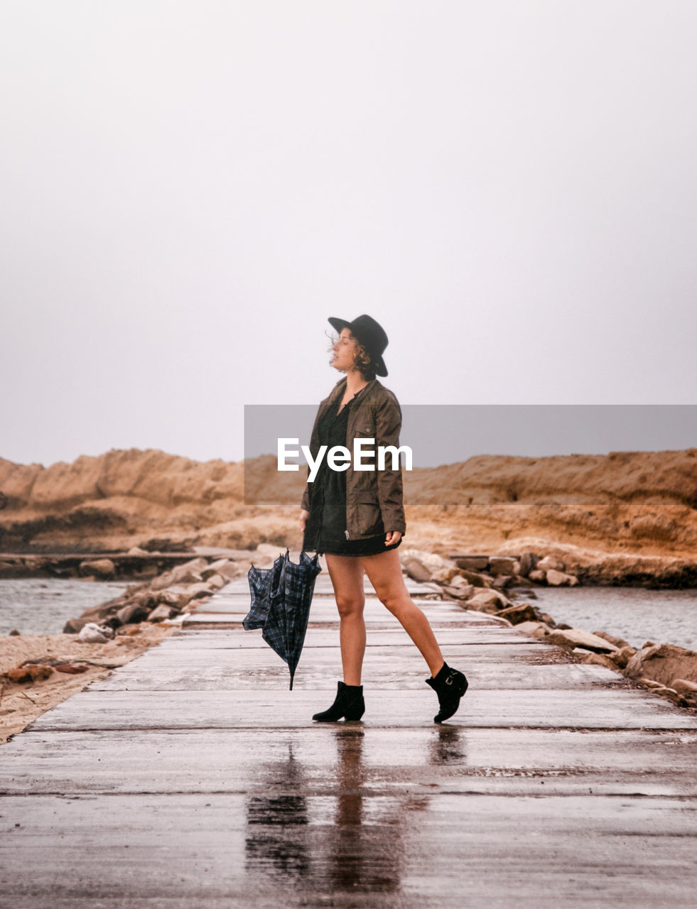 Young woman walking on pier against clear sky at beach