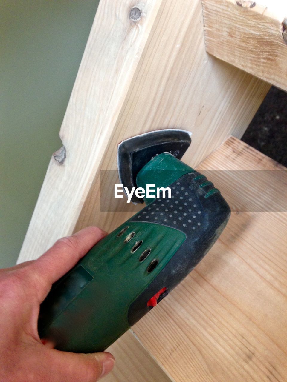 Cropped hand of man using power tool on wood at home