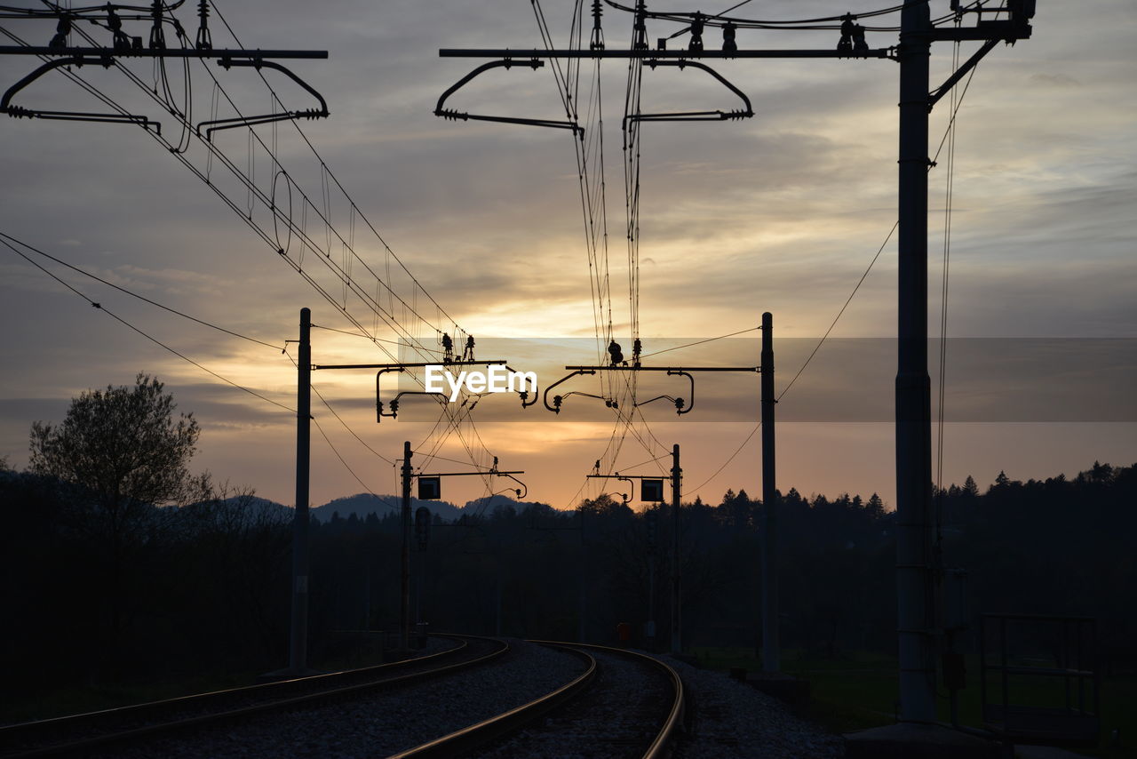 Silhouette railroad tracks against sky during sunset