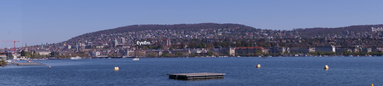 SAILBOATS IN BAY AGAINST CLEAR SKY