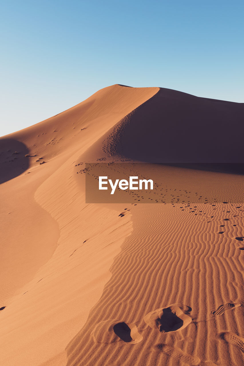 Sand dunes in desert against clear sky