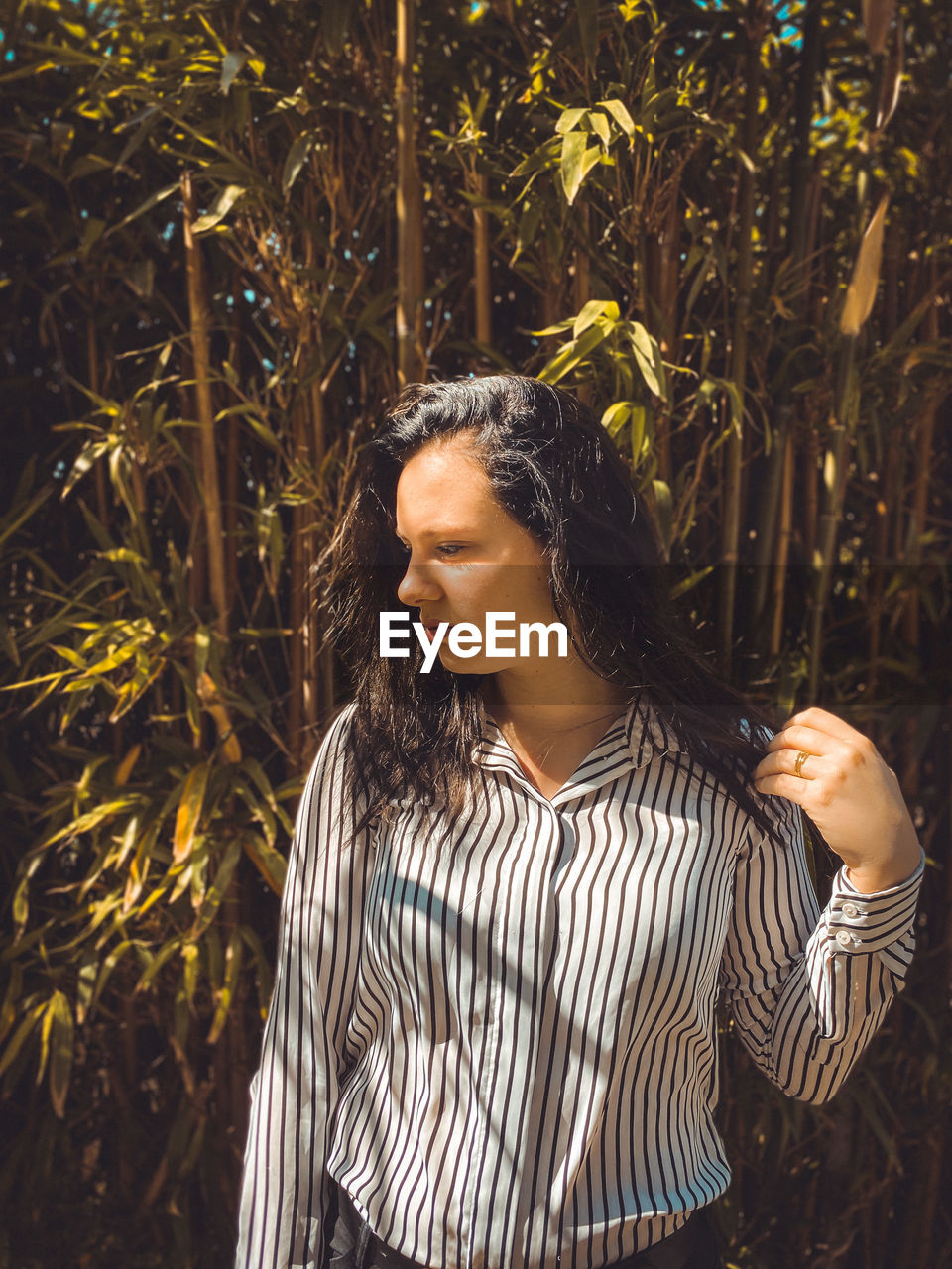 Woman looking away while standing by plants