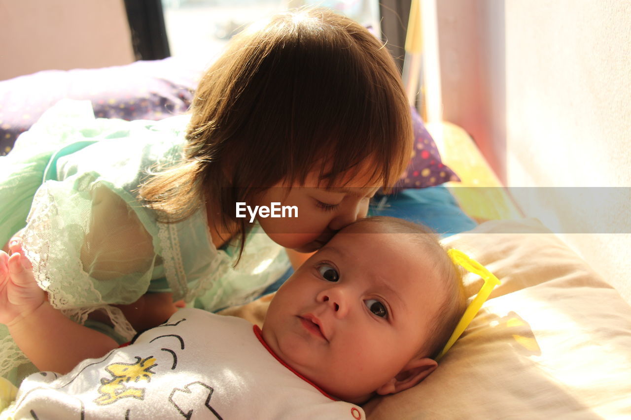 Close-up of cute girl kissing brother on forehead at home