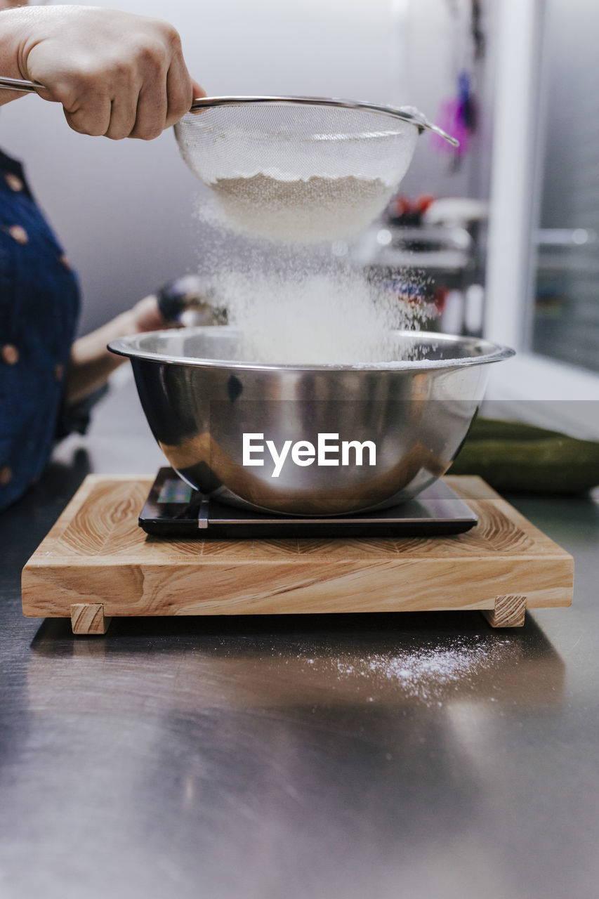 Midsection of woman sprinkling powdered sugar in container