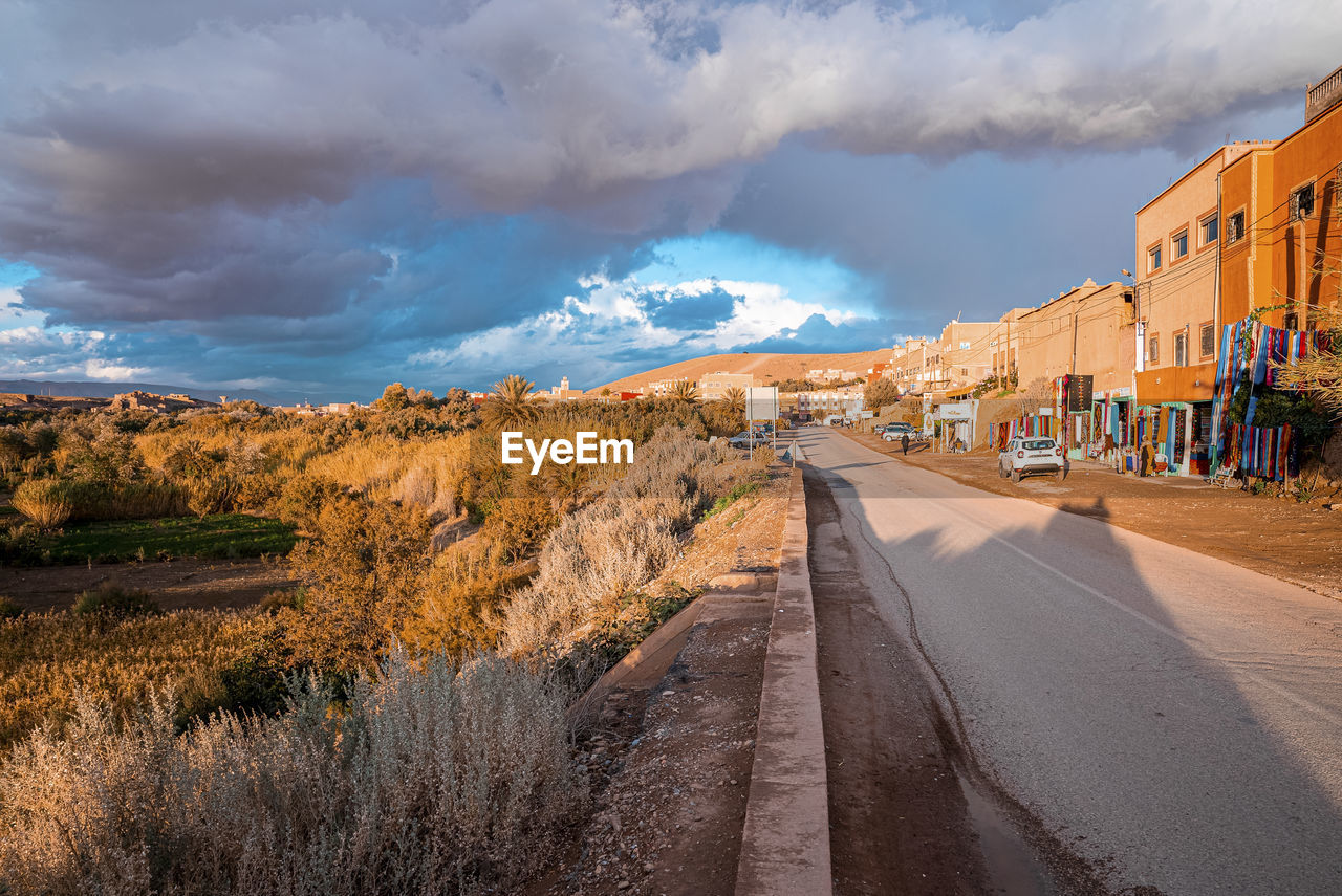 Residential houses with road against dramatic sky in sunny summer day