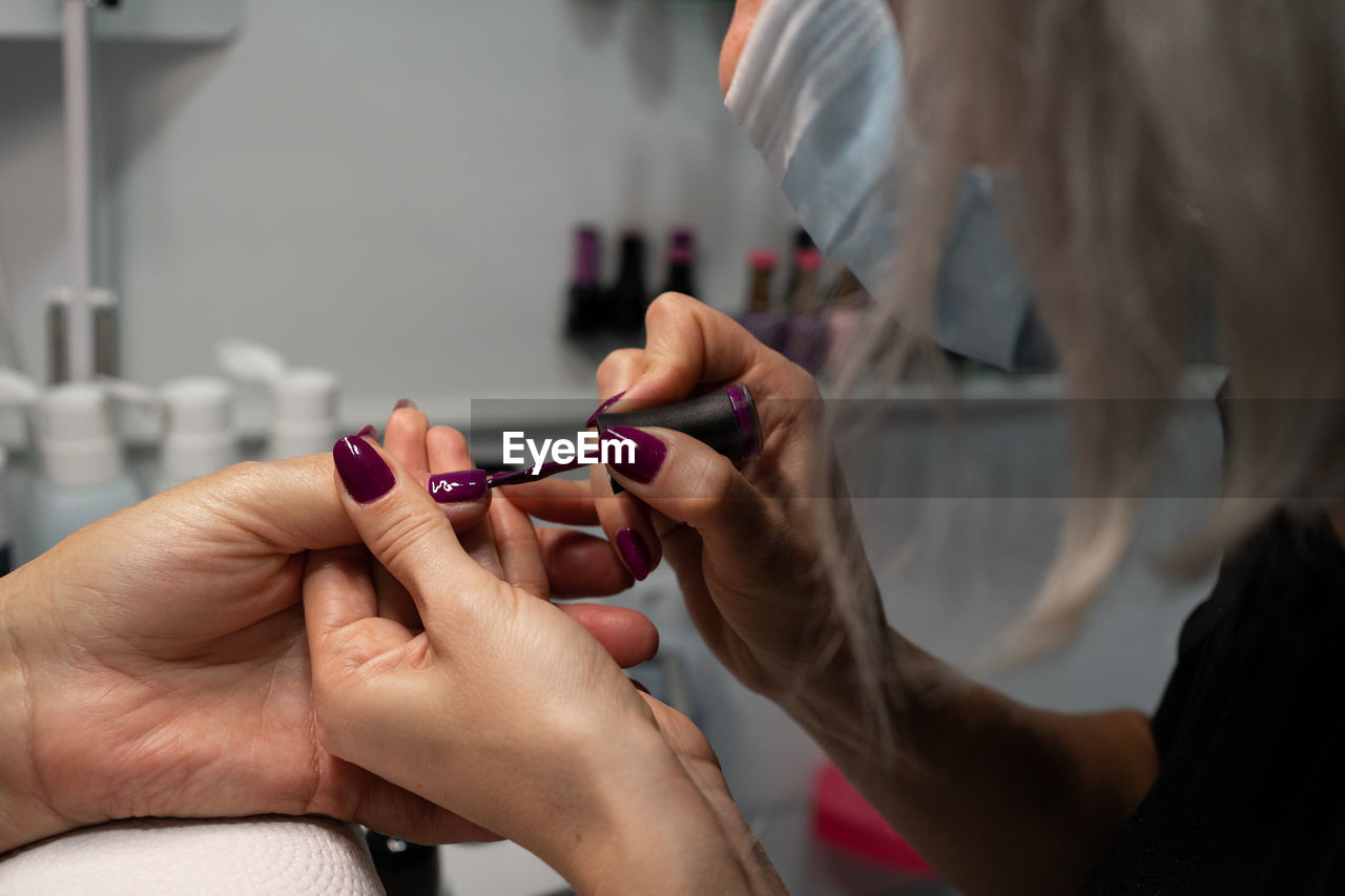 Senior woman in cosmetic salon doing manicure with specialist