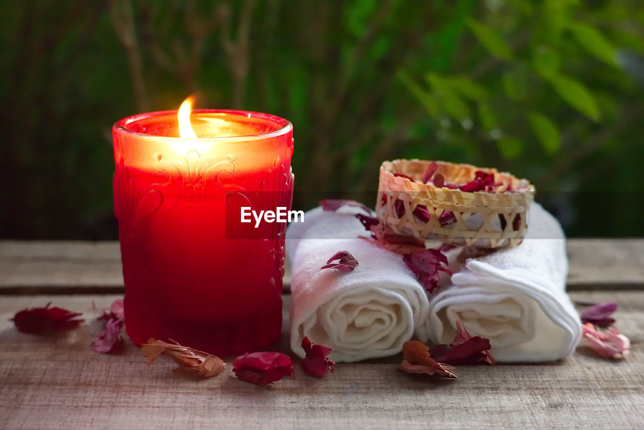 Close-up of burning candle on table with towel spa