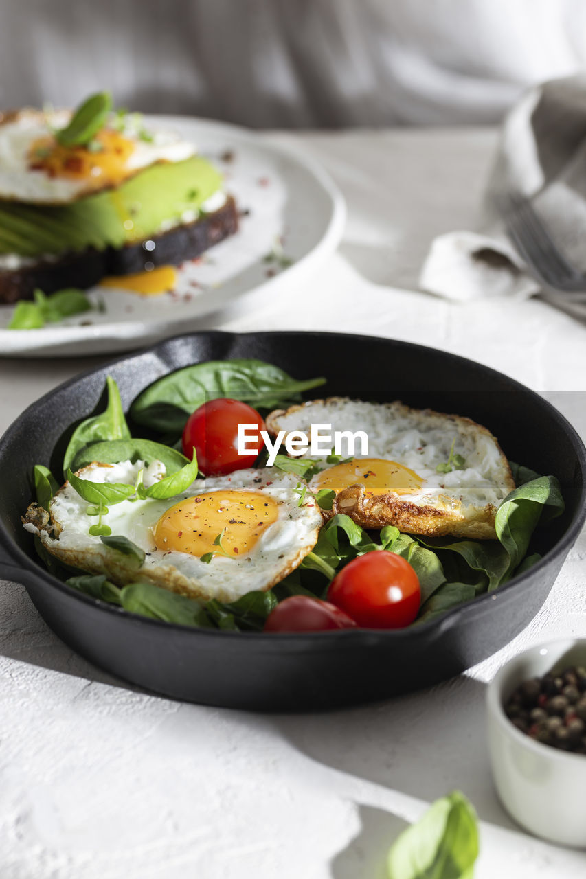 Breakfast with fried eggs and vegetables in a pan