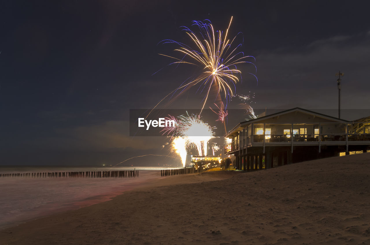 FIREWORK DISPLAY OVER SEA AT NIGHT