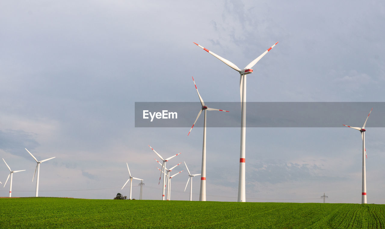 WIND TURBINES ON FIELD AGAINST SKY