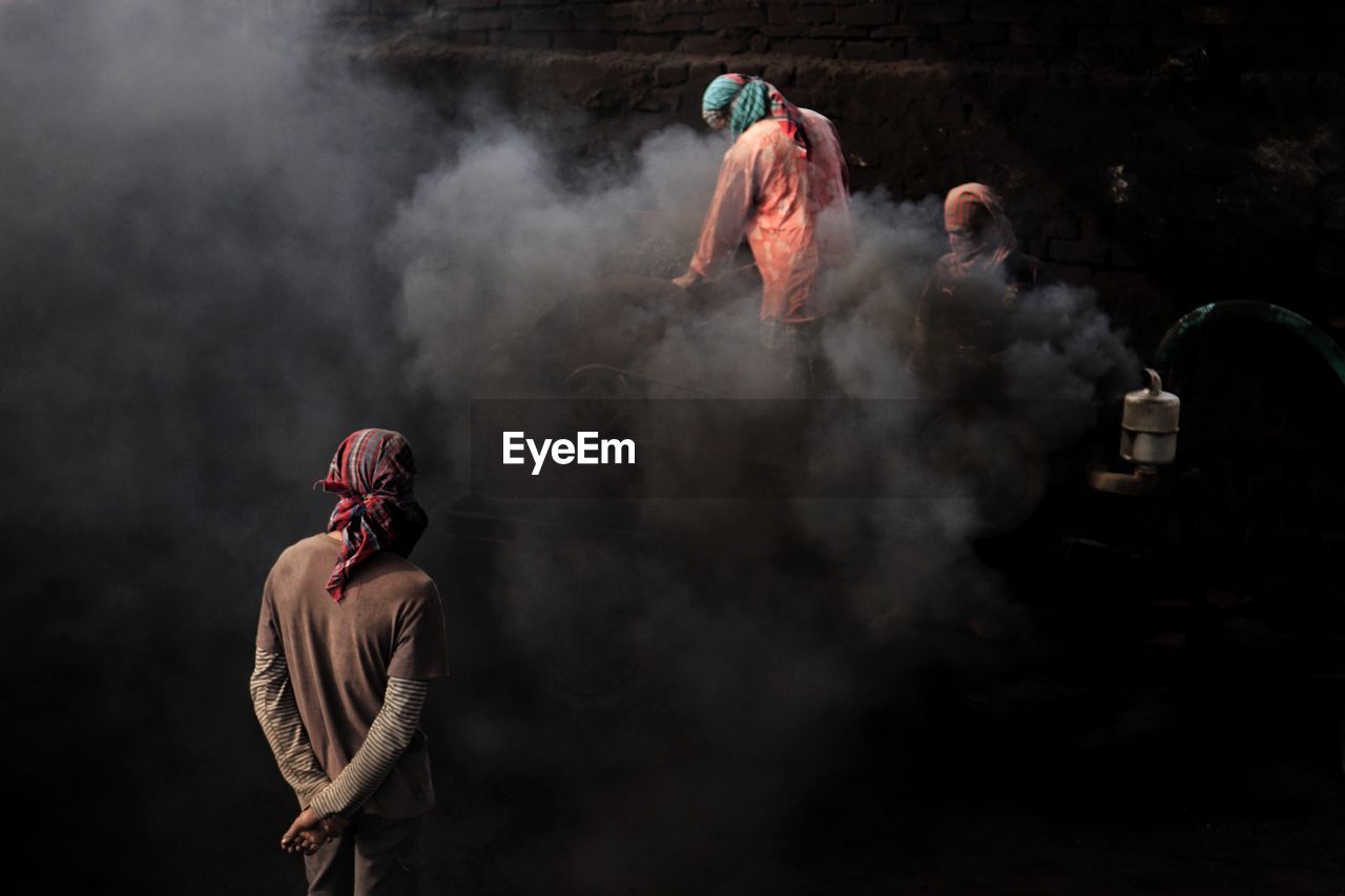 Rear view of people working at brick field in a over polluted environment 
