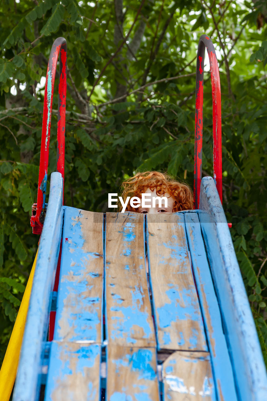Portrait of girl on slide against plants