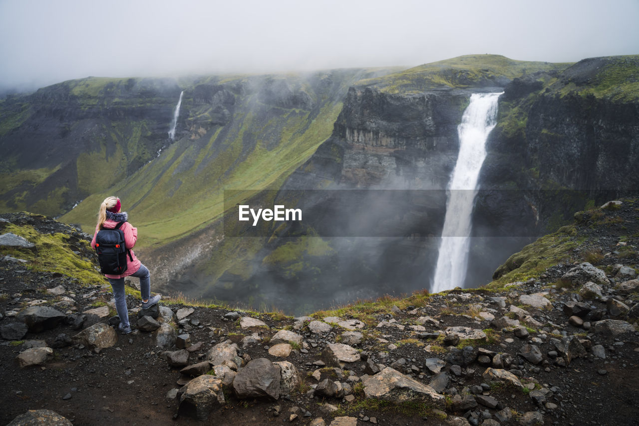 Woman with backpack enjoying haifoss waterfall of iceland highlands in thjorsardalur valley