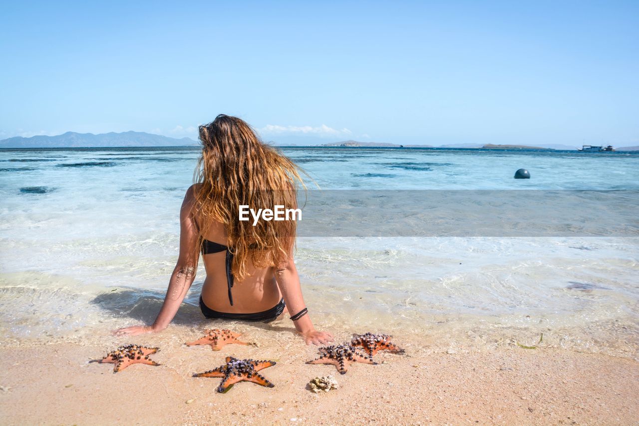 Girl alone in a sandy beach with clear blue sea 