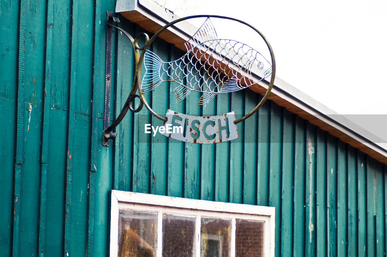 Low angle view of metallic fish sign on wall in city