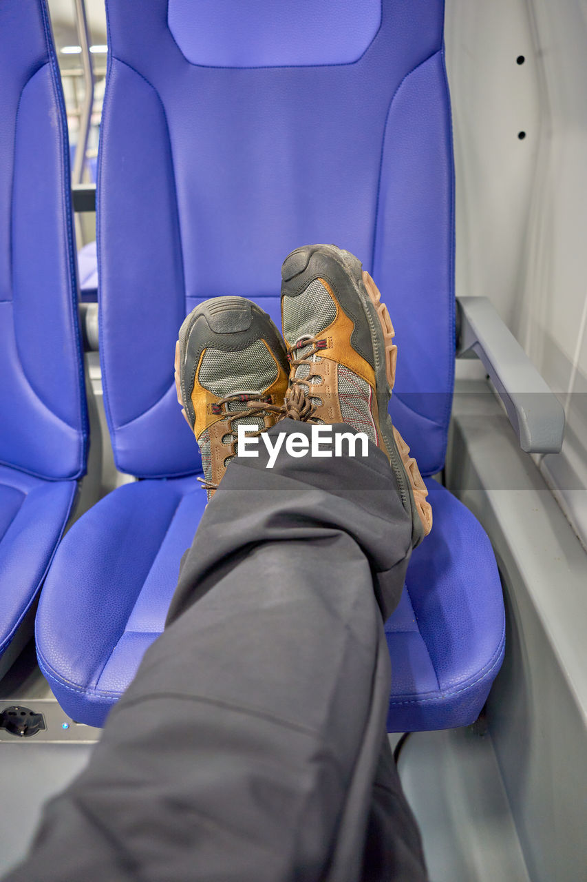 transportation, vehicle, vehicle interior, air vehicle, travel, human leg, vehicle seat, mode of transportation, airplane, low section, one person, shoe, personal perspective, adult, journey, seat, sitting, men, indoors, human limb, car seat, flying, airplane seat, limb, passenger, footwear, relaxation, high angle view, human foot, lifestyles