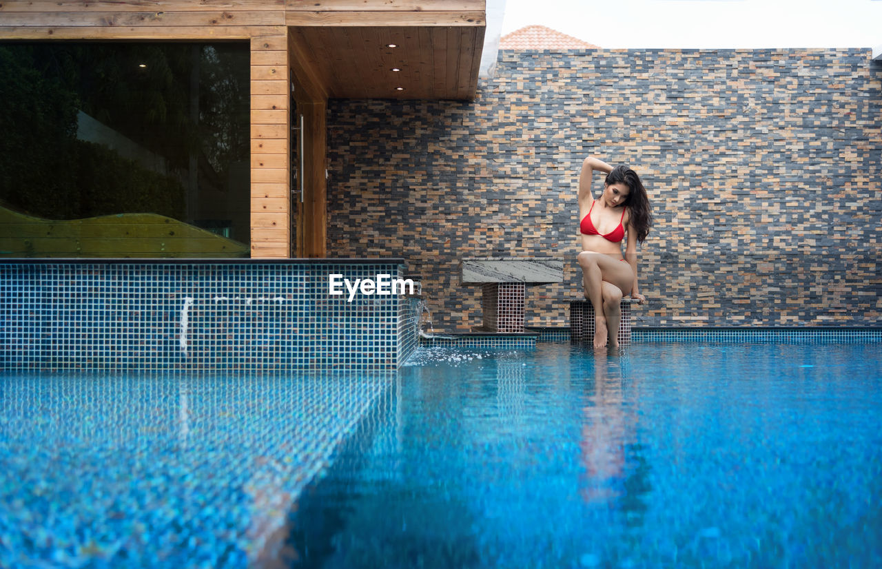 WOMAN STANDING AT SWIMMING POOL