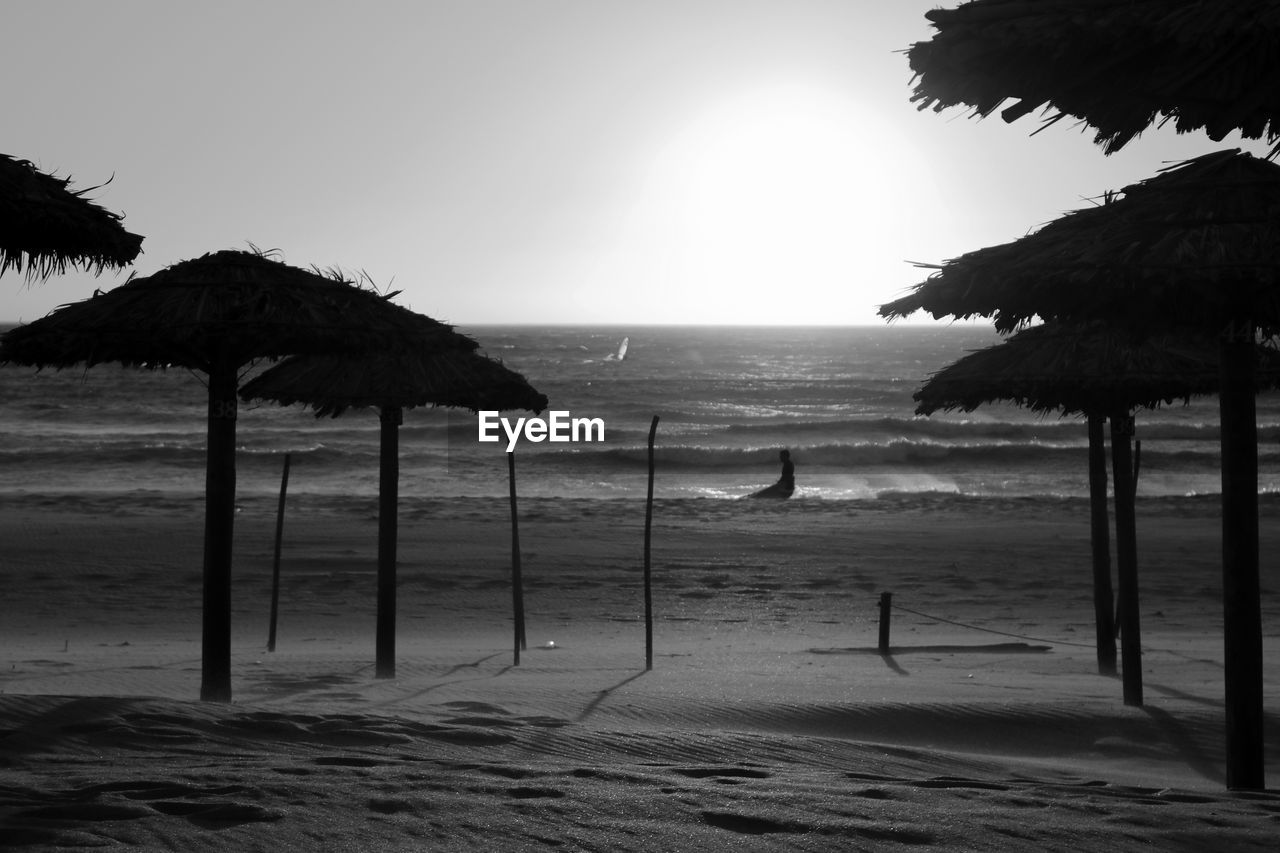 Thatched roofs at beach against sky