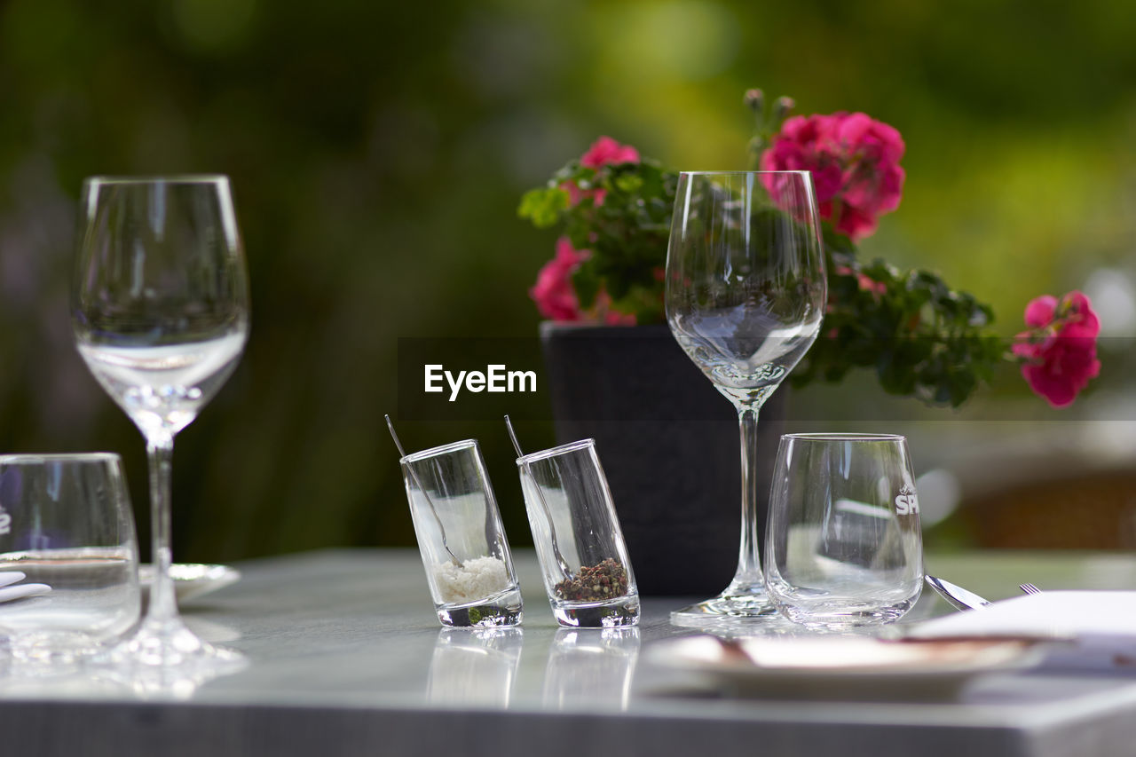 Wineglasses by flower vase on dining table