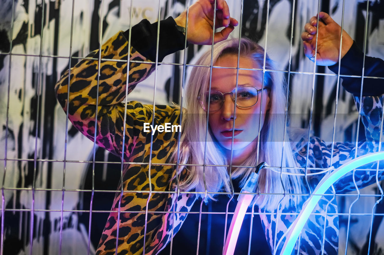 Portrait of young woman seen through fence