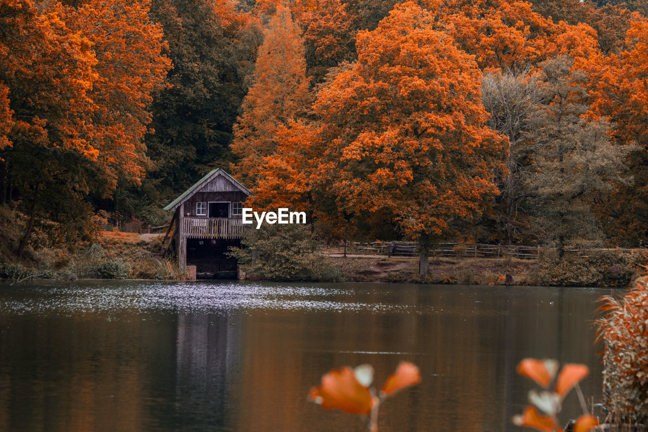 Scenic view of lake and boathouse in forest during autumn