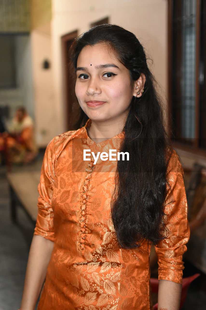 Portrait of smiling young woman standing indoors