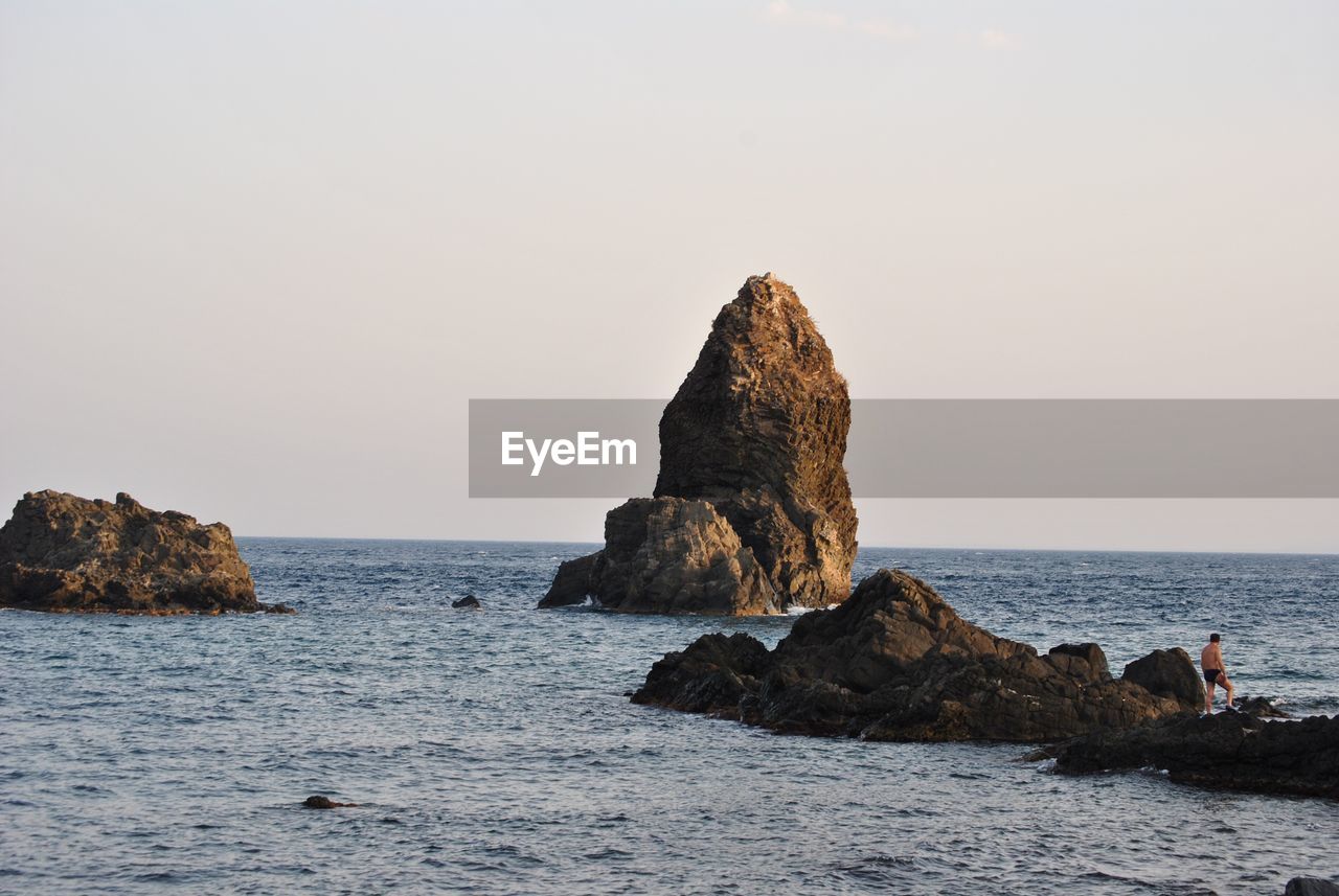 Rock formations on shore against clear sky