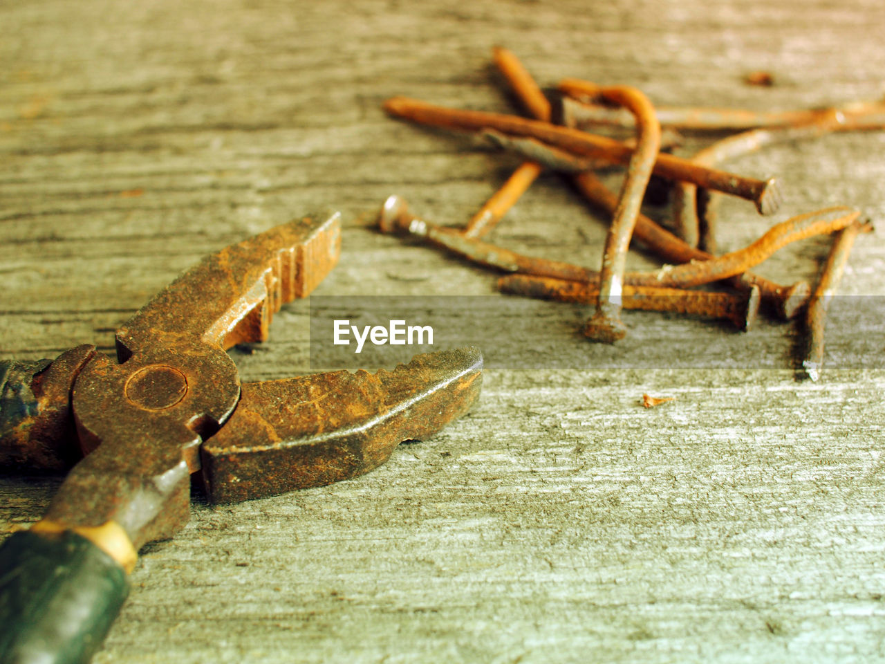 Close-up of old rusty pliers and nails on wooden table