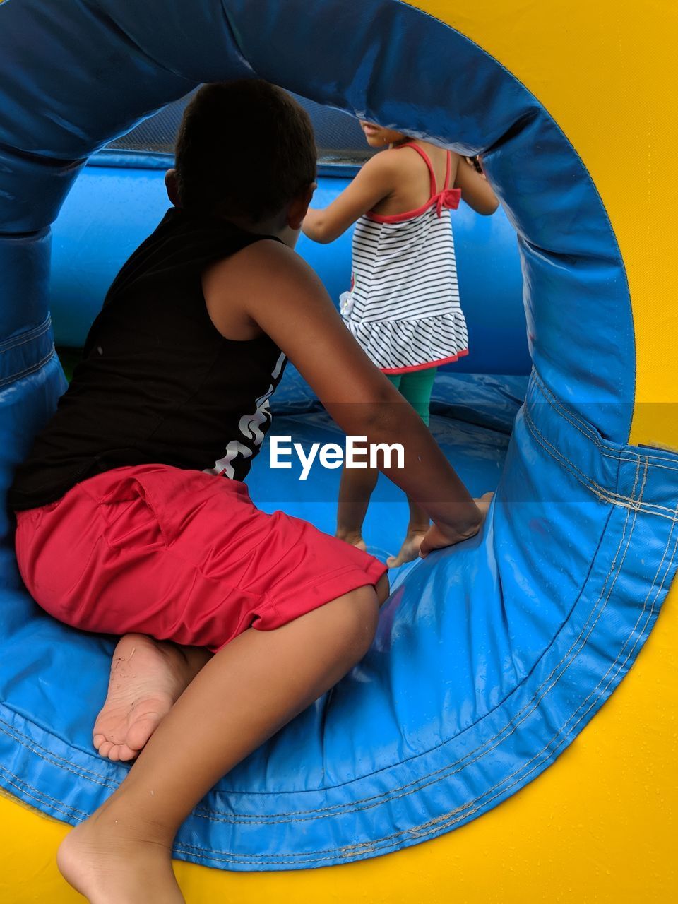 Rear view of siblings playing in bouncy castle