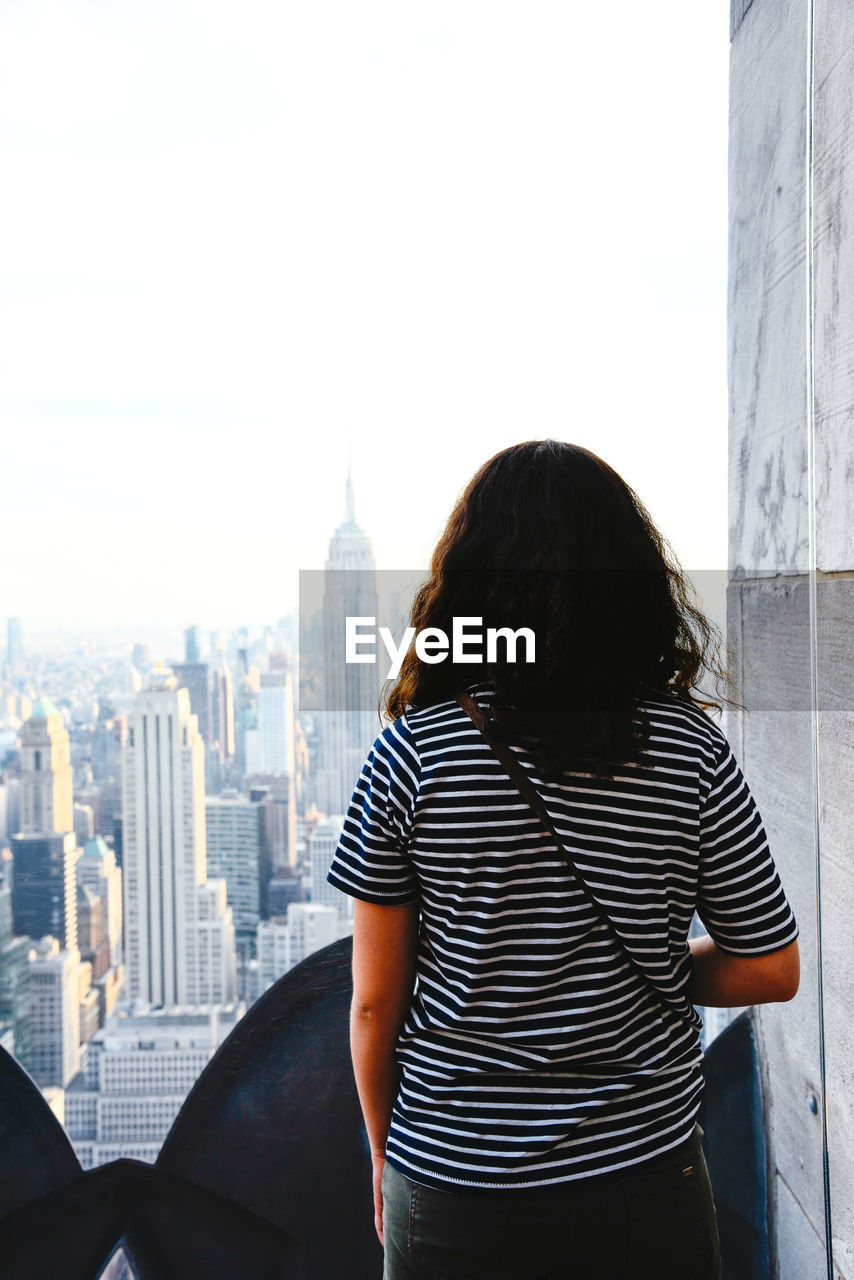 Girl looking at manhattan skyline from rooftop