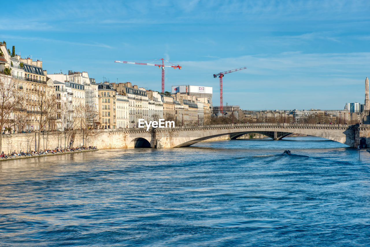 Arch bridge over river against buildings in city