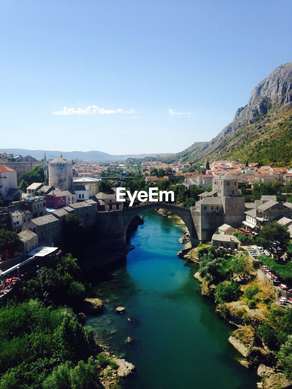 High angle view of river amidst buildings against blue sky