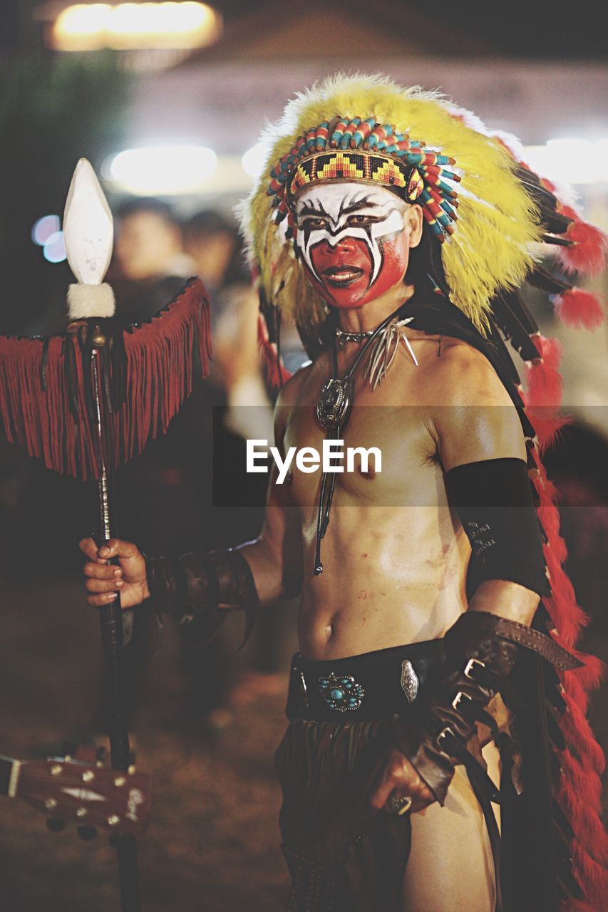 Man looking away while wearing tribal costume at night