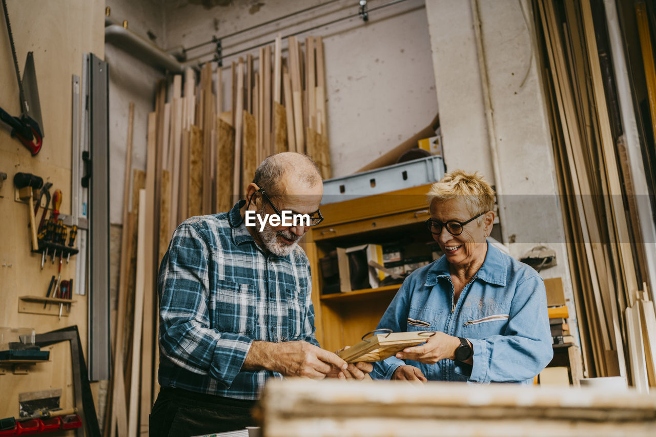 Male and female senior entrepreneurs discussing over frame at repair shop