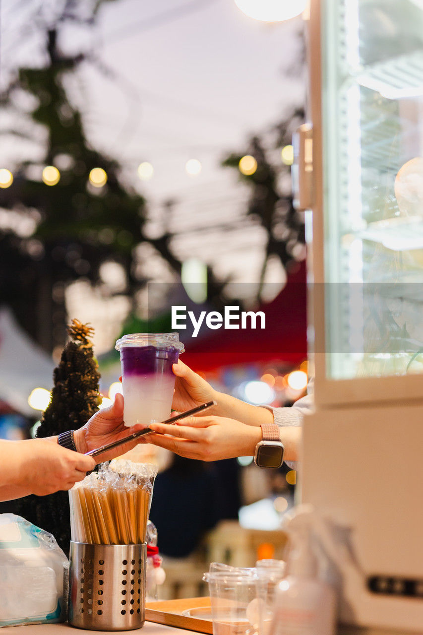 Woman hand passing a drink to customer in a shop.