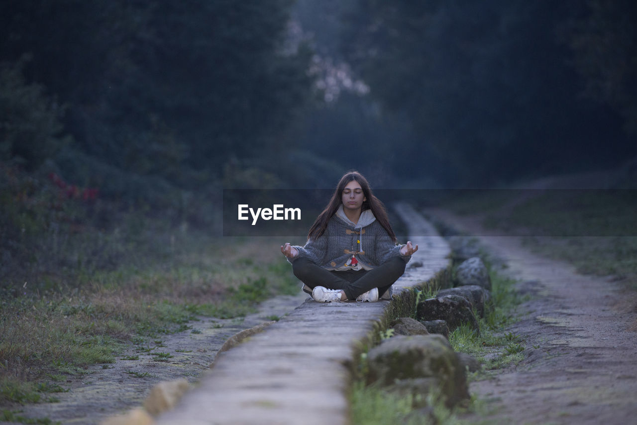 Young woman doing yoga on pathway