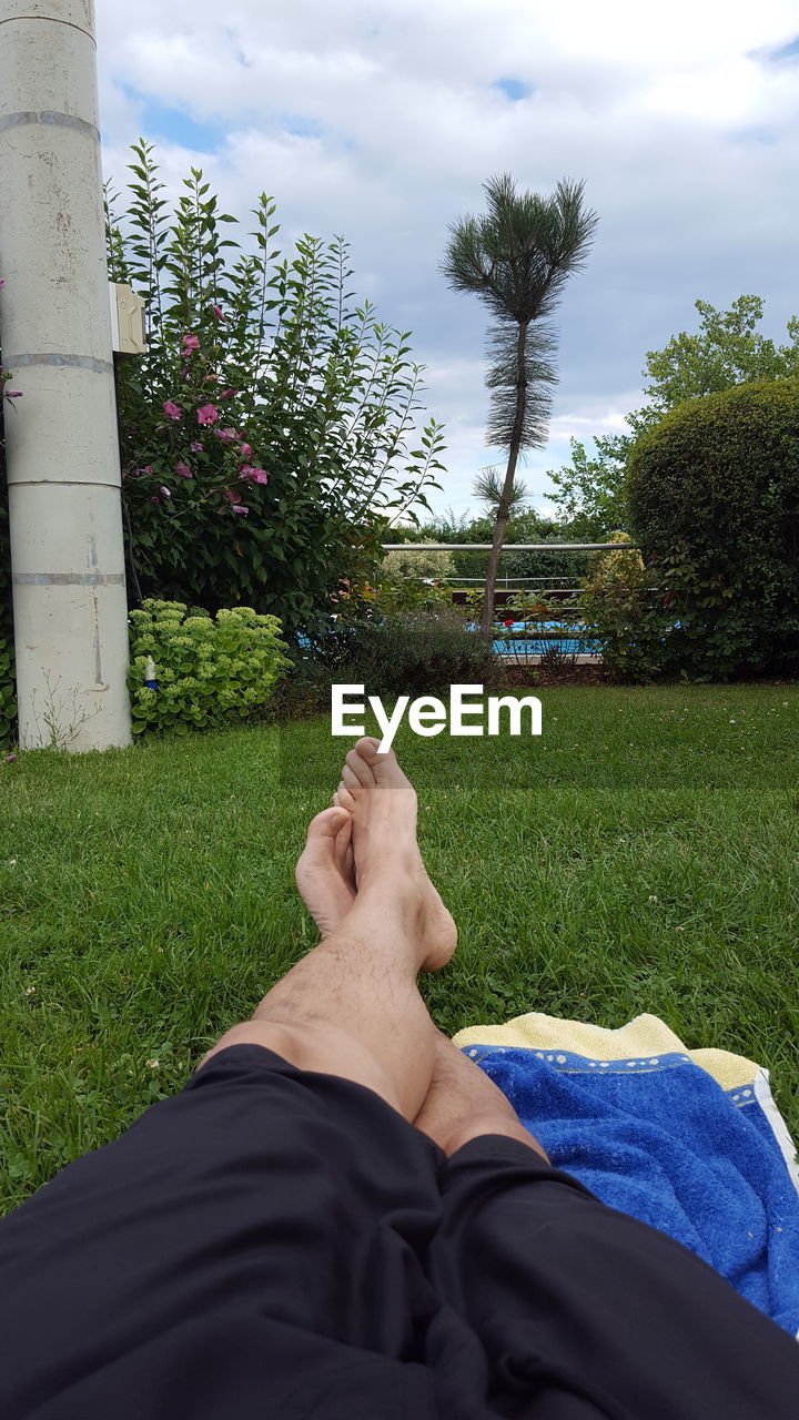 Low section of man relaxing on grassy field