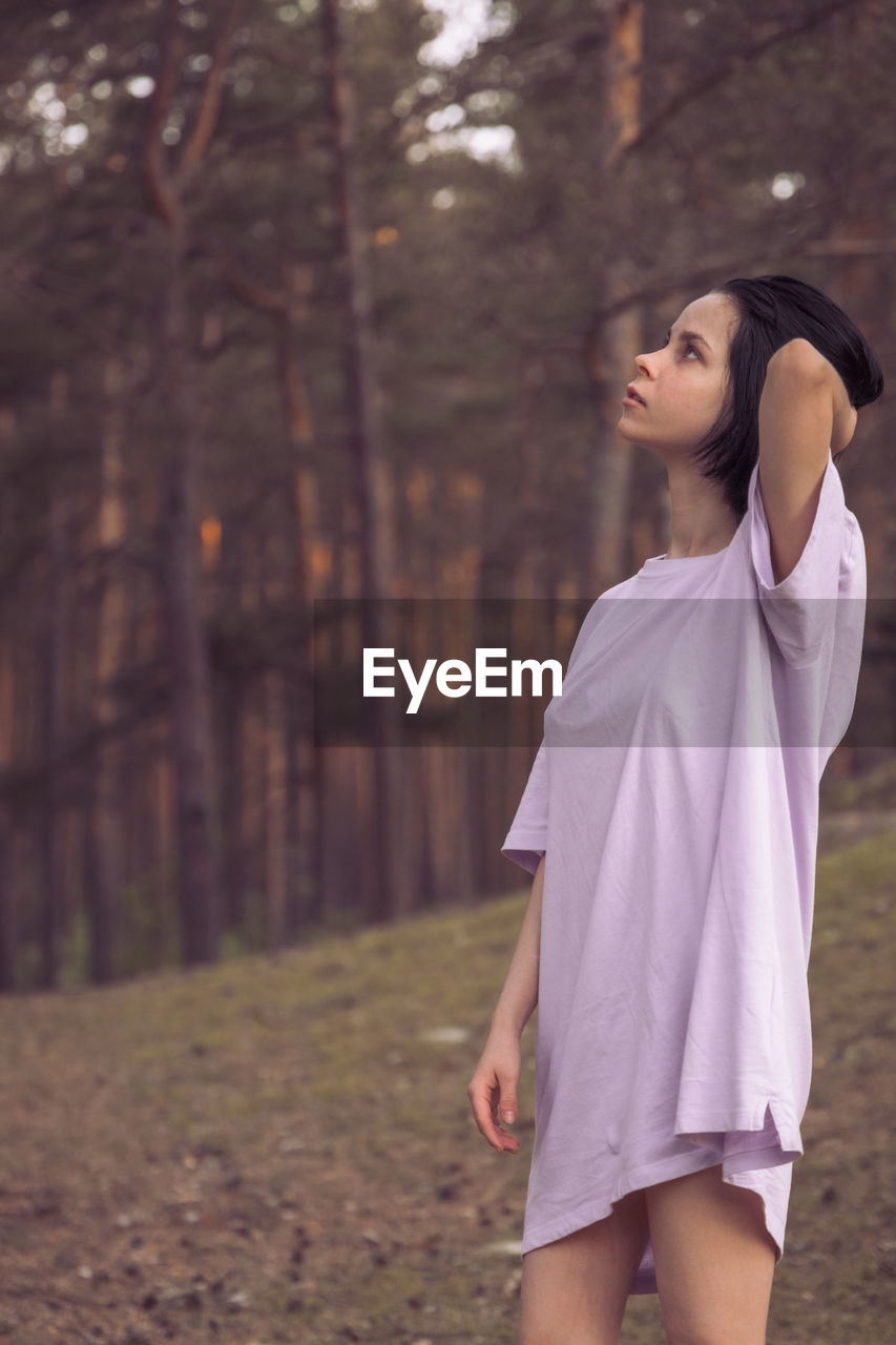 Full length of woman standing on field in forest