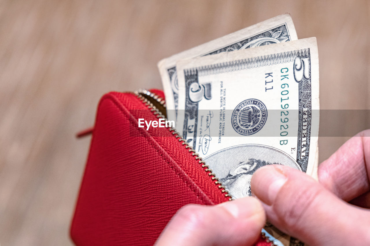 CLOSE-UP OF A HAND HOLDING RED PAPER WITH TEXT