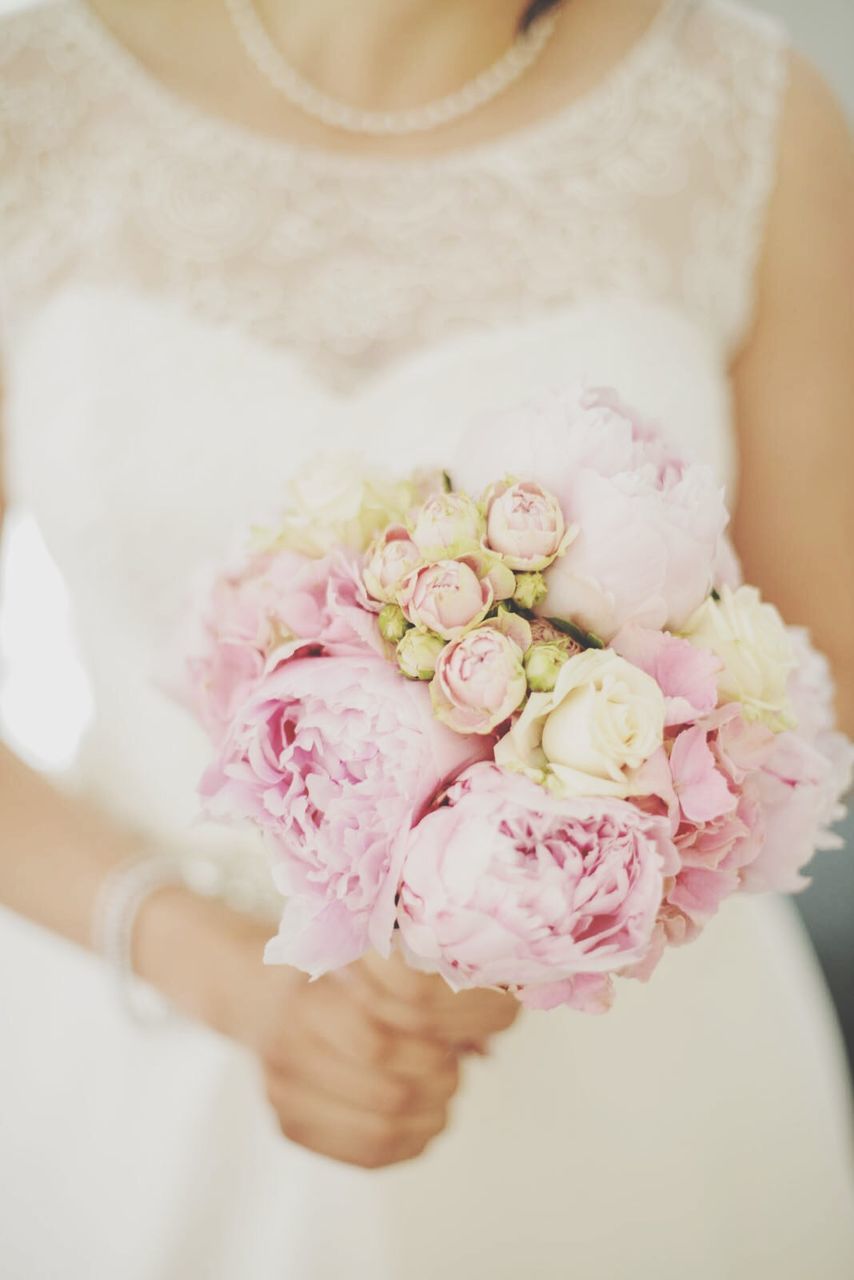 Mid section of a bride holding bouquet