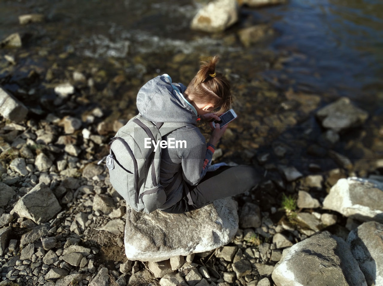 HIGH ANGLE VIEW OF PERSON ON ROCK AT LAKESHORE