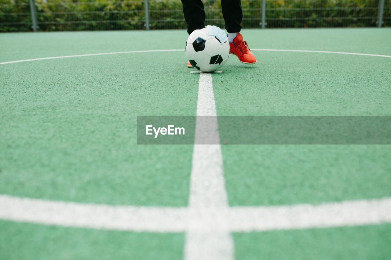 Low section of person playing soccer ball on grass