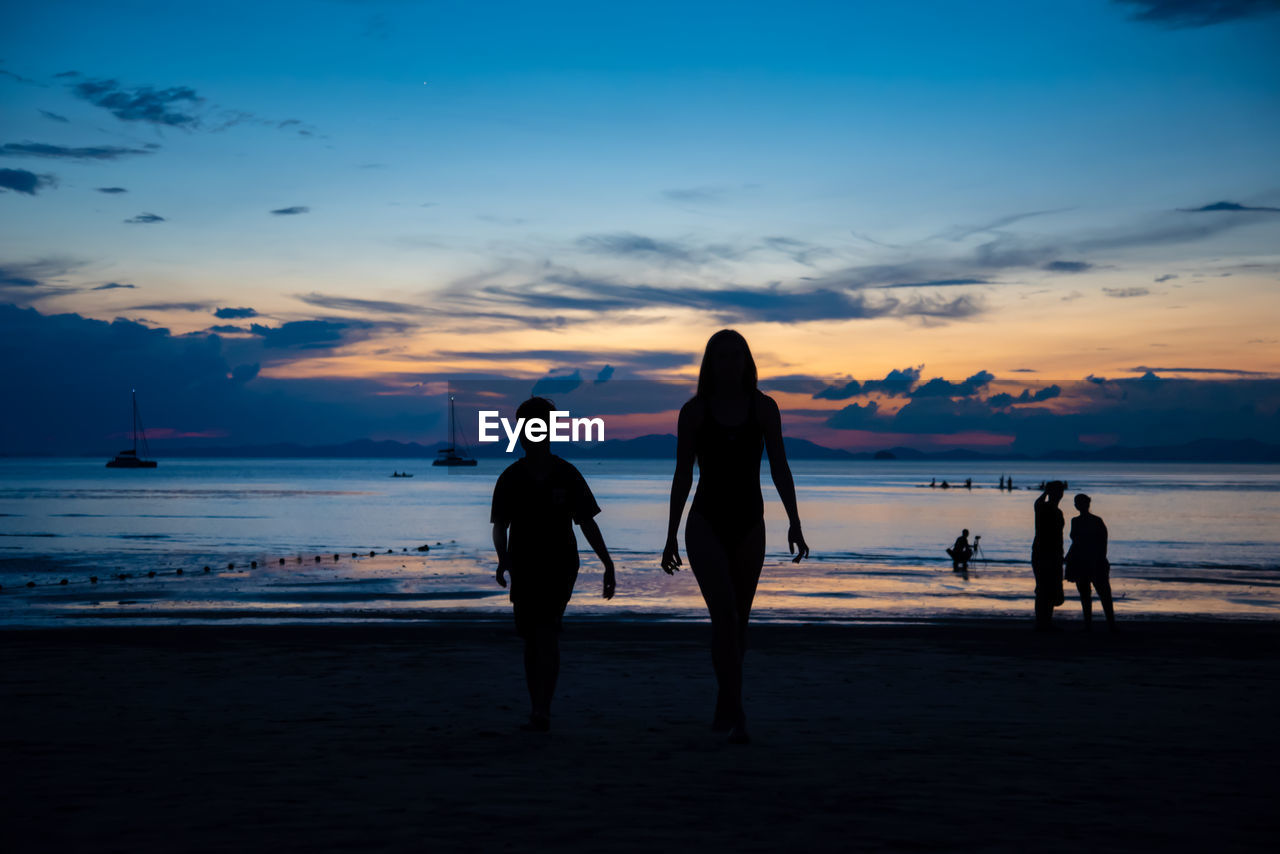 SILHOUETTE PEOPLE ON BEACH AGAINST SUNSET SKY