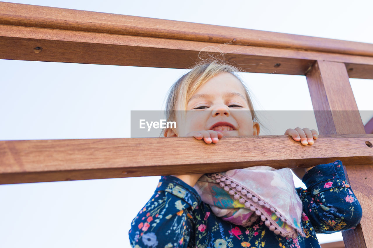 PORTRAIT OF CUTE GIRL PLAYING ON WOODEN OUTDOORS