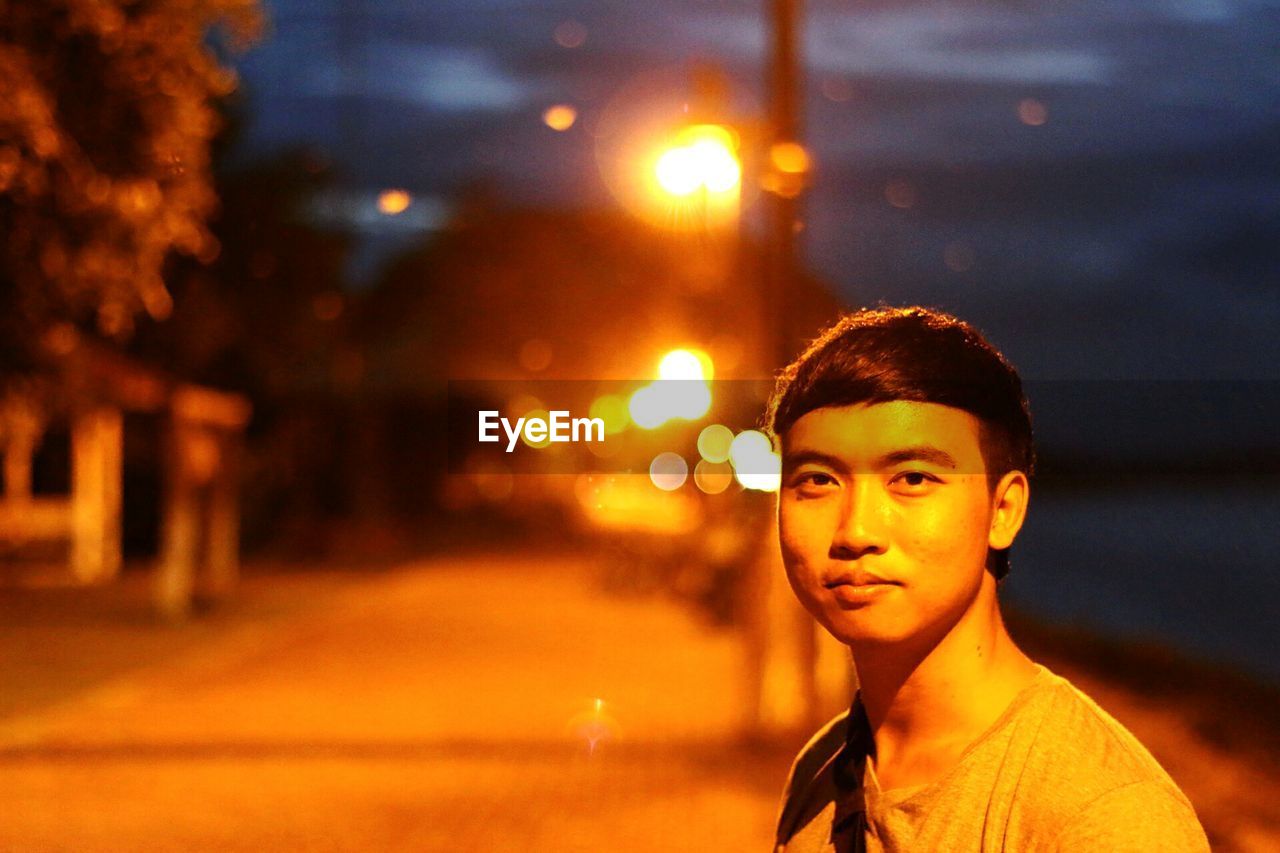 Portrait of young man on illuminated street at night