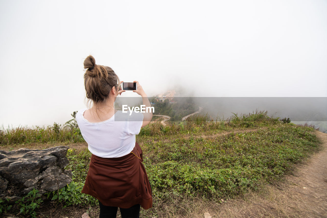 Rear view of woman photographing on mountain