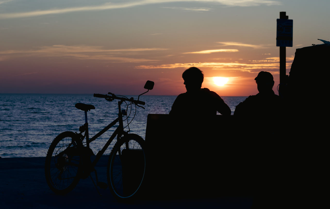 sunset, sky, silhouette, bicycle, sea, water, transportation, nature, beach, evening, horizon, men, land, cloud, beauty in nature, mode of transportation, vehicle, activity, adult, leisure activity, horizon over water, travel, lifestyles, dusk, vacation, orange color, scenics - nature, trip, two people, outdoors, ocean, sunlight, sun, holiday, tranquility, back lit, sports, person, relaxation