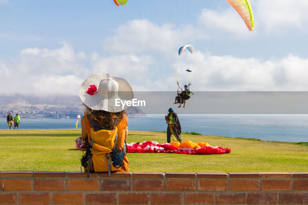 Paragliding on landscape against clouds